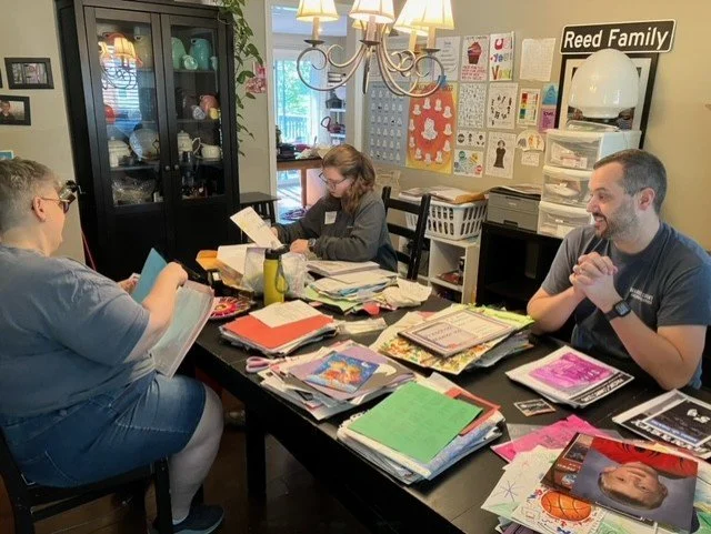Volunteers gathered around a table assembling packets.